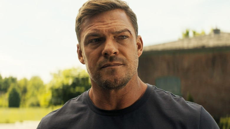 Alan Ritchson sebagai Jack Reacher berdiri di luar di Reacher