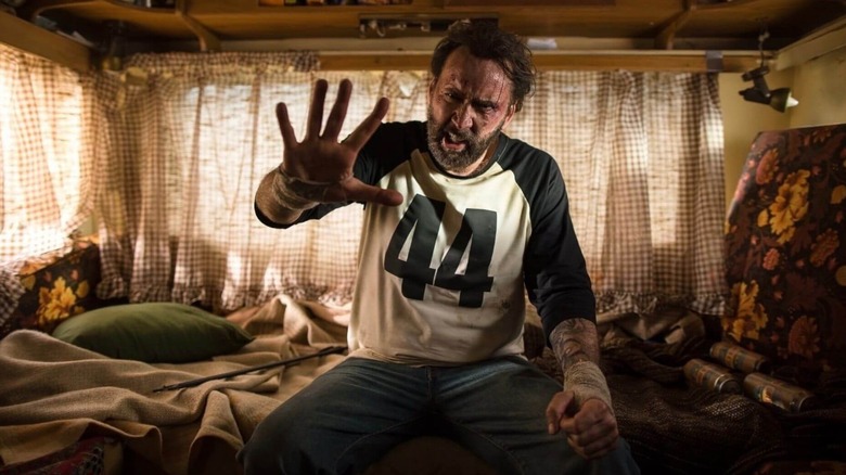 Nicolas Cage sebagai Red Miller mengangkat tangan kanannya di depannya di Mandy