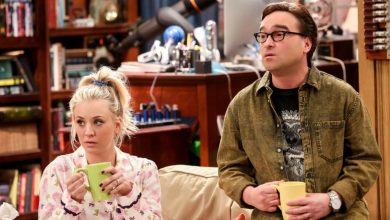 Penny di sofa dan Leonard duduk di lengan memegang cangkir kopi di Teori Big Bang