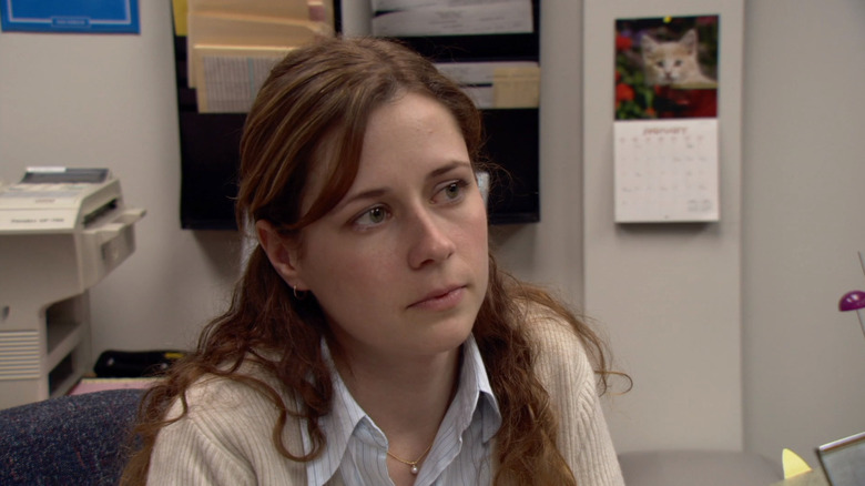 Jenna Fischer sebagai Pam duduk di mejanya di kantor musim 1