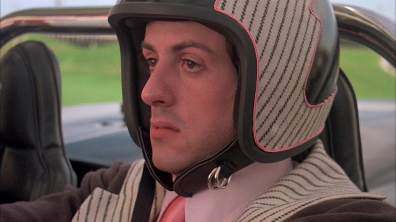 Sylvester Stallone As Joe 'Machine Gun' Viterbo duduk di mobilnya mengenakan helm di Death Race 2000