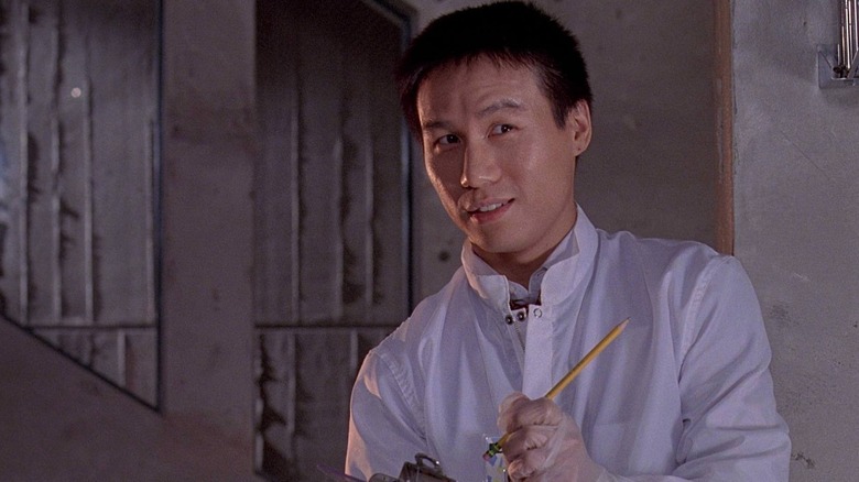 BD Wong sebagai Dr. Henry Wu memegang papan klip dan pensil di lab di Jurassic Park