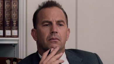 Kevin Costner membelai dagunya sebagai Kenneth O'Donnell dalam tiga belas hari