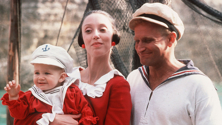 Robin Williams sebagai Popeye tersenyum sebagai Shelley Duvall sebagai Olive oyl cradles swee'pea baby in popeye