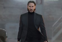 Keanu Reeves sebagai John Wick berjalan dengan mobil yang terbakar di gudang di John Wick
