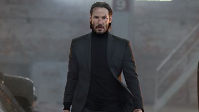 Keanu Reeves sebagai John Wick berjalan dengan mobil yang terbakar di gudang di John Wick