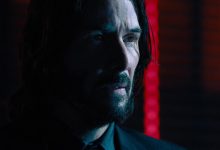 Keanu Reeves 'John Wick melihat ke kejauhan melawan lampu neon di John Wick Bab 4