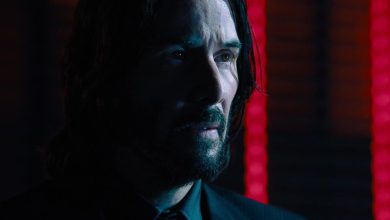 Keanu Reeves 'John Wick melihat ke kejauhan melawan lampu neon di John Wick Bab 4