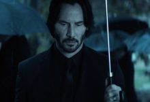 Keanu Reeves 'John Wick berdiri memegang payung di pemakaman di John Wick