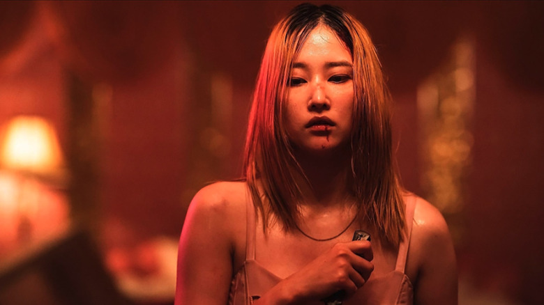Jang Ok-Ju (Jeon Jong-Seo) memegang pisau di rumah kaca neon-lit di Ballerina (2023)