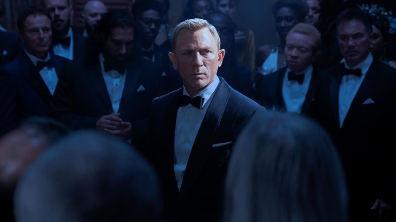 Daniel Craig sebagai James Bond dikelilingi oleh kerumunan di tuksedo dalam waktu singkat untuk mati