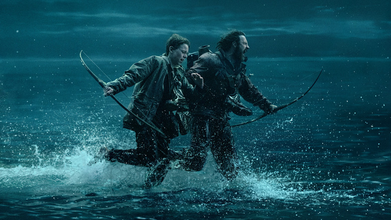 Aaron Taylor-Johnson sebagai Jamie dan Alfie Williams sebagai putranya Spike berlari melintasi perairan yang dangkal jauh dari bahaya dalam 28 tahun kemudian