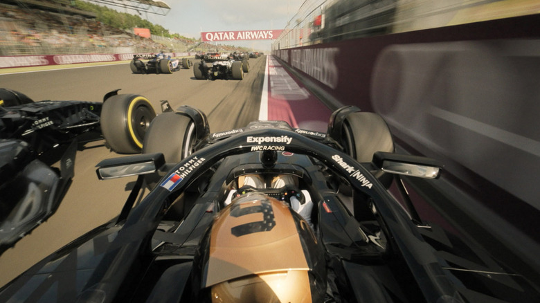 Mobil APXGP berlomba melawan mobil lain di dekat dinding di F1